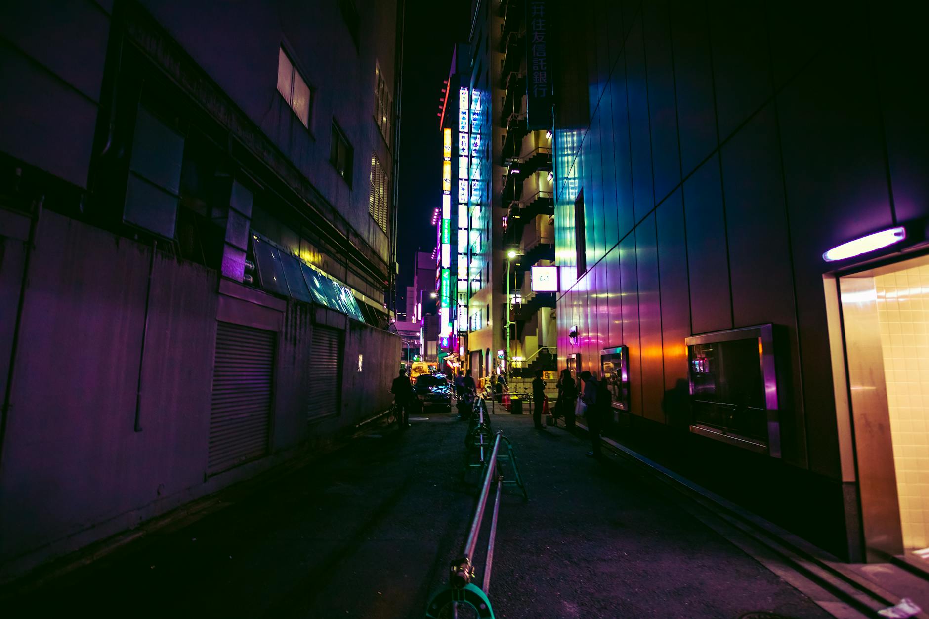 Dark urban alley illuminated by colorful neon lights, capturing vibrant night city life.