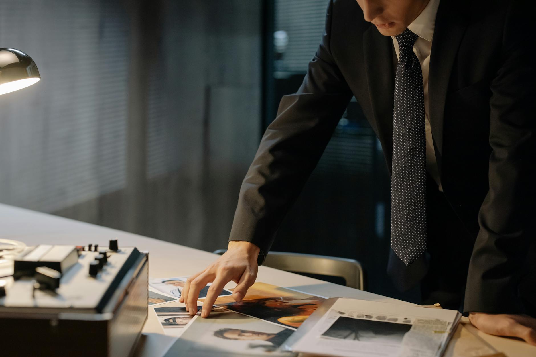 Investigator reviewing evidence photos during a night investigation in an office setting.