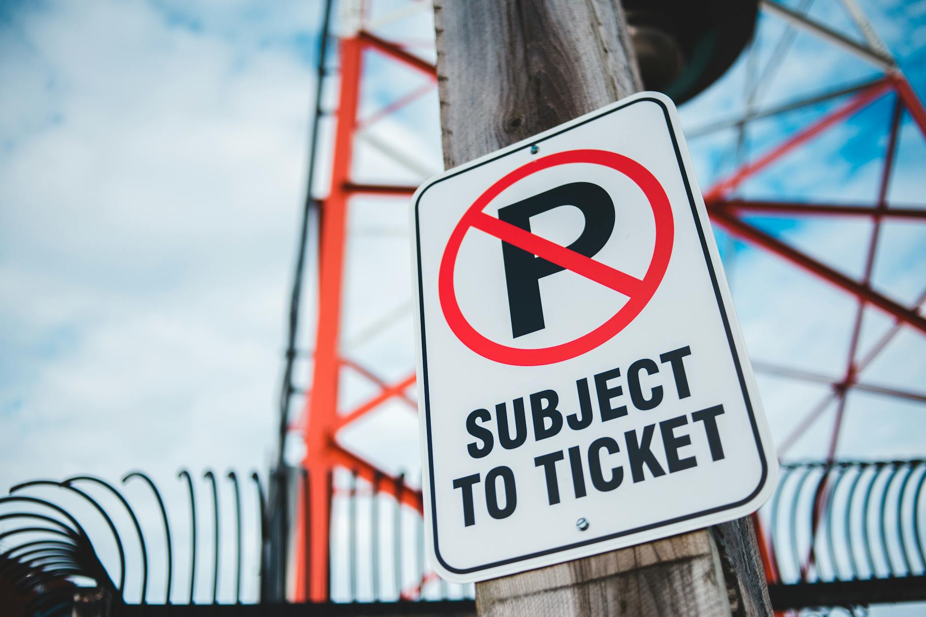 Close-up of a no parking sign with a tower in the background, emphasizing traffic restrictions and warnings.